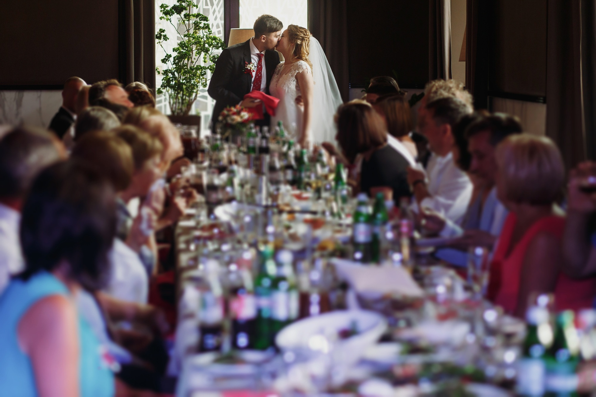 Couple de jeunes mariés s'embrassant lors d'une réception de mariage dans un restaurant